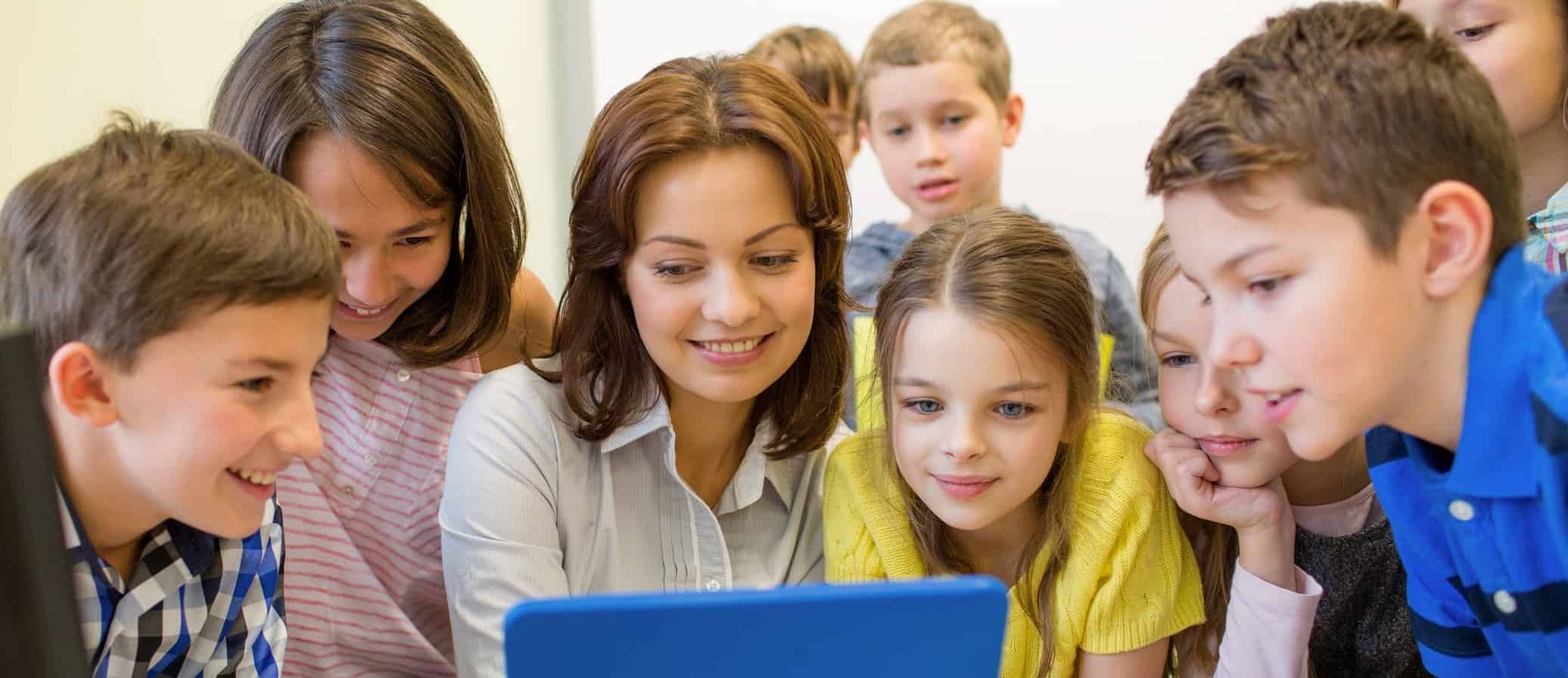 Une enseignante et ses élèves découvrent ensemble une ressource numérique sur une tablette