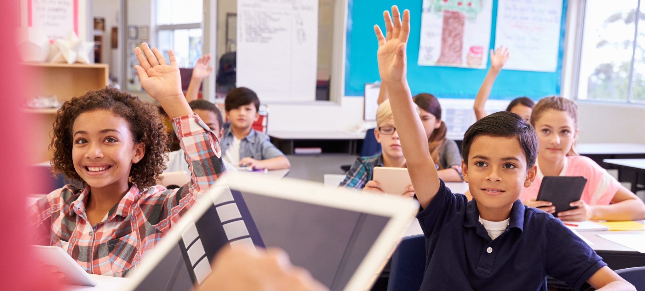 Élèves levant la main dans une classe équipée de tablettes